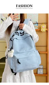 Gros plan sur le sac bleu clair avec motif étoilé en relief, poche avant zippée et pompon doux