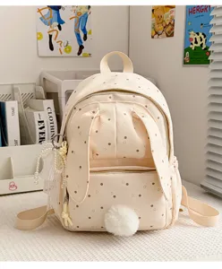 Détail du sac à dos crème avec pois bruns, oreilles de lapin, pompon doux et breloques en perles