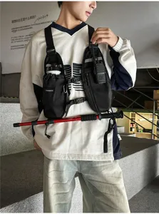 Model wearing a black utility chest bag with adjustable straps, multiple pockets and a radio