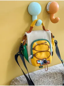 Sac coloré suspendu à un mur jaune, avec détail de cordon à l’avant et bandoulière réglable