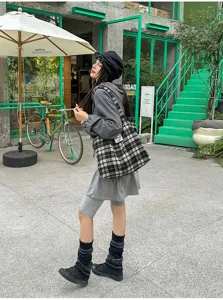 Street-style scene showing a model carrying a black, white and beige plaid tote outdoors
