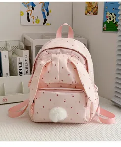 Tissu rose à pois, détail avant en oreilles de lapin et pompon blanc dans un coin bureau