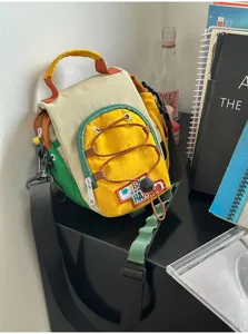 Détail d’un sac en nylon colorblock avec poche jaune, cordon, zip et bandoulière réglable