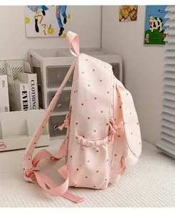 Vue latérale d’un sac à dos rose à pois, avec oreilles de lapin et pompon en peluche