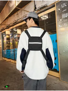 Street view of a black sling bag worn on the back, with adjustable straps and a reflective strip
