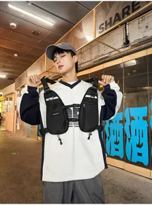 Model wearing a black nylon chest pack with adjustable straps, zip pockets and reflective trim