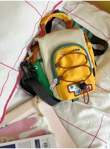 Détail du sac coloré avec poche zippée jaune, cordon brun et bandoulière noire réglable