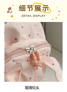 Gros plan sur les tirettes métalliques lisses à cordons roses, sur le tissu rose à pois du sac