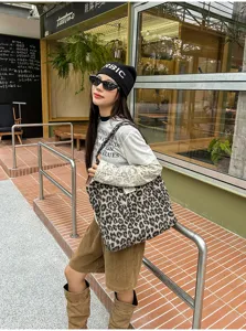 Street-style view of a model carrying a large leopard-print tote over her shoulder outside a café