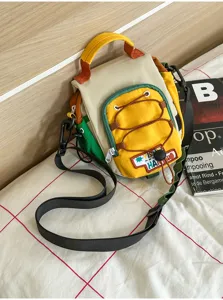 Détail du sac bicolore avec poche zippée jaune, cordons, poignée et bandoulière réglable