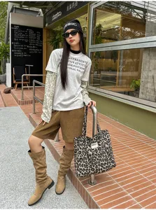 Street-style view of a model carrying a leopard-print canvas tote with a casual layered outfit