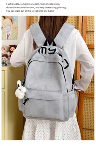 Vue arrière d’un sac gris à étoiles en relief, sangles noires et breloque lapin blanc en peluche