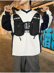 Man wearing a black chest harness bag with adjustable straps, zip pockets and reflective trim