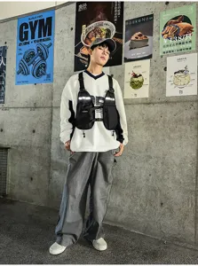 Street-style view of a model wearing a black tactical chest vest over a white sweatshirt