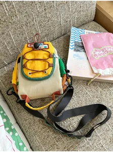 Vue du petit sac en nylon colorblock, avec rabat jaune, cordon élastique et bandoulière noire