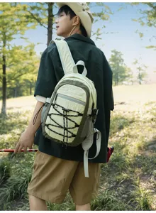 Person trägt im Freien einen hellbeige-olivgrünen Rucksack mit Frontschnürung und Seitentasche