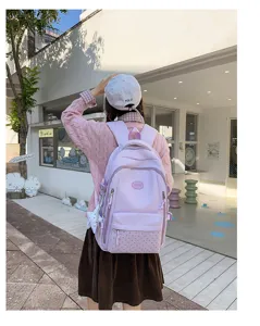 Vue de dos d’une personne portant un sac rose, avec poche avant à pois et bretelles bien visibles