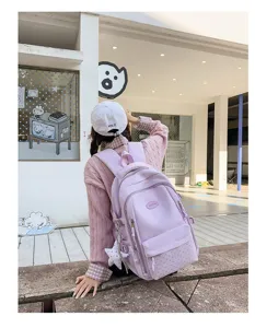 Vue de dos d’une élève portant un sac lavande à pois, avec un pendentif étoile suspendu