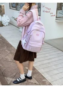 Vue de côté d’un modèle portant un sac à dos lilas, avec poche avant à pois et breloque étoile