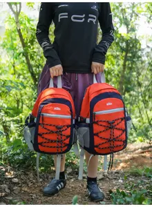Zwei orange-rote und marineblaue Rucksäcke mit Reflektorstreifen und Kordeln im Wald