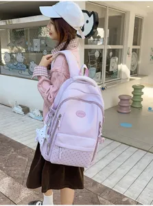 Vue de dos d’une personne portant un sac à dos lavande, motif étoilé, breloque et plusieurs poches
