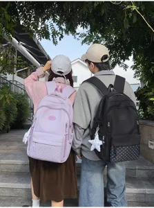 Deux élèves portent dehors des sacs lilas à pois et noirs à étoiles, avec des breloques blanches