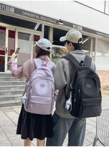 Deux personnes de dos portent des sacs roses et noirs à panneaux à pois avec des breloques nœud