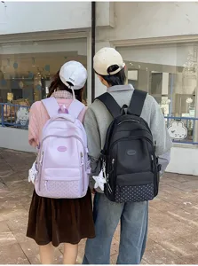 Vue arrière de sacs à dos roses et noirs, avec panneaux inférieurs à pois, portés à l'extérieur