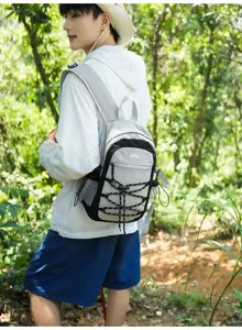 Seitenansicht einer Person mit grauschwarzem Rucksack und gekreuzten Gummizügen im Wald