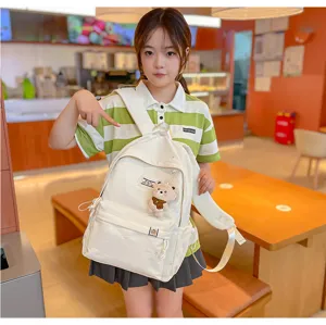 Une élève présente un sac à dos crème avec un pendentif ourson dans un café chaleureux