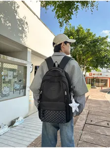 Vue arrière d’un sac à dos noir, avec motif étoilé sur la poche basse et pendentif étoile blanc