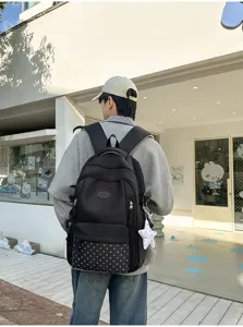 Vue arrière d’une personne portant un sac noir, avec poche à étoiles et breloque étoile blanche