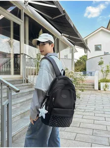 Sac à dos noir avec panneau inférieur à étoiles blanches et breloque étoile, porté dehors