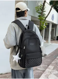 Vue de dos d’une personne portant un sac noir, avec poche à étoiles blanches et breloque étoile