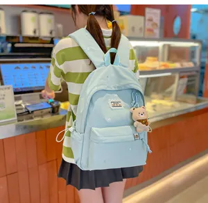 Dans un café, une élève porte un sac à dos bleu clair, brodé d’étoiles, avec un pendentif ourson