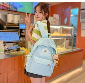 Une femme porte dans un café un sac à dos bleu clair brodé avec un pendentif ourson