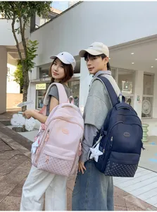 Deux jeunes présentent des sacs à dos rose et bleu marine, ornés de breloques étoilées en ville.