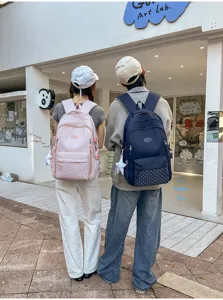 Deux personnes portent devant une boutique des sacs à dos roses et bleu marine à pois blancs