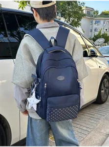 Vue arrière d’une personne portant un sac bleu marine, poche avant à étoiles et breloque étoile