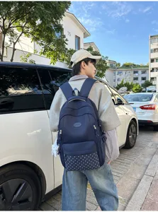 Vue de dos d’une personne portant un sac à dos bleu marine à panneaux étoilés dans une rue ensoleillée
