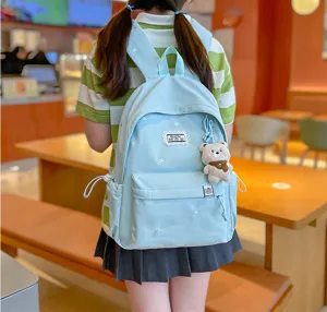 Élève portant un sac à dos bleu clair, brodé d’étoiles, avec un petit pendentif ourson dans un café