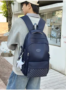 Vue d’un sac à dos bleu marine porté, avec poche inférieure à étoiles et breloque décorative