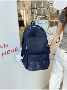 Gros plan sur la poche à étoiles, l’écusson rond et le pendentif étoile blanc du sac à dos
