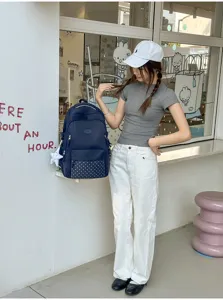 Vue portée d’un sac à dos bleu marine, avec poche avant à pois et breloque étoile blanche