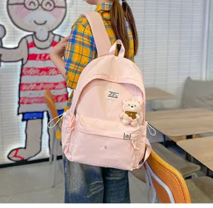 Sac rose porté sur le dos, avec broderie florale, un pendentif ourson et une poche zippée à l'avant