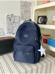 Détail d’un sac à dos bleu marine, avec poche avant à étoiles et pendentif blanc en forme d’étoile