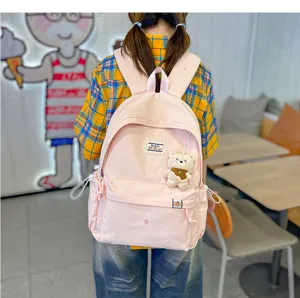 Vue de dos, sac à dos rose clair avec poche zippée et petit ourson en peluche accroché