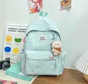 Vue de la poche du sac à dos vert menthe, avec broderies étoilées et breloque ourson en peluche