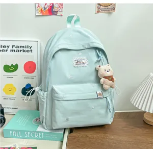 Tissu vert menthe, broderies d’étoiles, poche zippée à l’avant et petit ourson suspendu