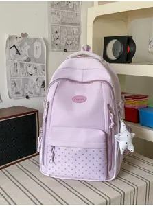 Sac à dos lavande posé sur une table, avec poche avant à étoiles et breloque étoile blanche